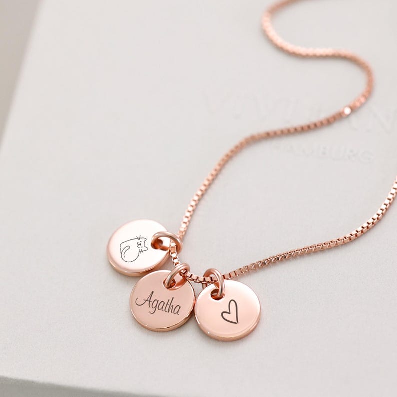 Op de afbeelding: Roze gouden ketting met drie bedels: een kat, een hart en een bedel met de gravure "Agatha".