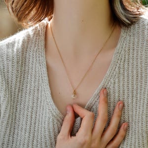May include: A gold chain necklace with a small glass pendant containing a dried flower.