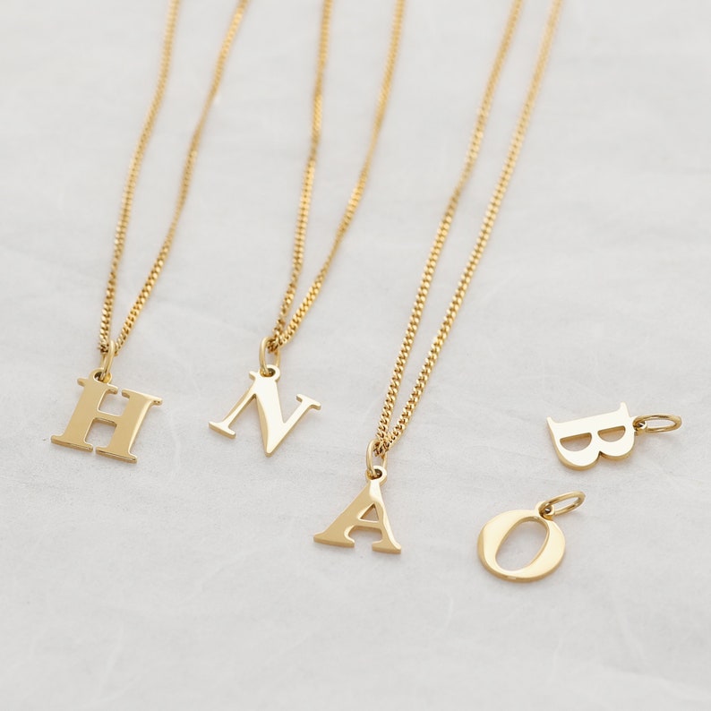 May include: Four gold necklaces with initial pendants. The pendants are the letters H, N, A, and O.