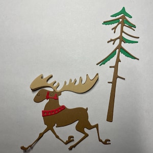 May include: A brown paper cut-out of a moose with red antlers and a red collar running towards a green paper cut-out of a pine tree.