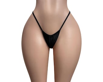 May include: A black thong featuring a minimalist design with thin side straps and a small, triangular front panel. The garment is constructed from a solid black fabric with a subtle sheen, providing a simple and clean aesthetic for this piece of underwear.