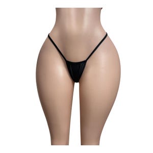 May include: A black thong featuring a minimalist design with thin side straps and a small triangular front panel. The garment is constructed from a smooth, solid-colored fabric that sits low on the hips, providing a sleek and simple appearance.