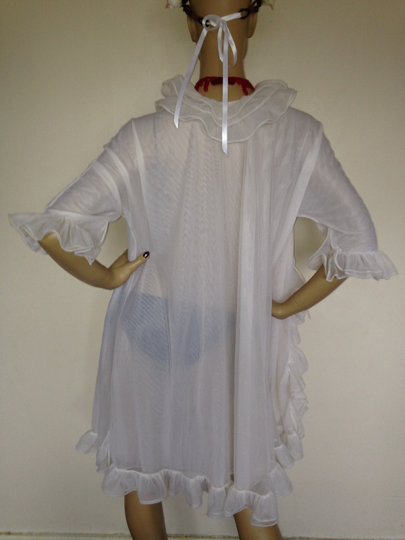 May include: White sheer nightgown with a ruffled collar and sleeves. The gown has a ruffled hem and is made of a lightweight fabric.