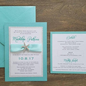 May include: A turquoise blue invitation card with silver glitter accents. The card features the text "Madeline Patricia" and the date "10.8.17". The card also includes details about a Bat Mitzvah celebration, including the time, location, and RSVP information.