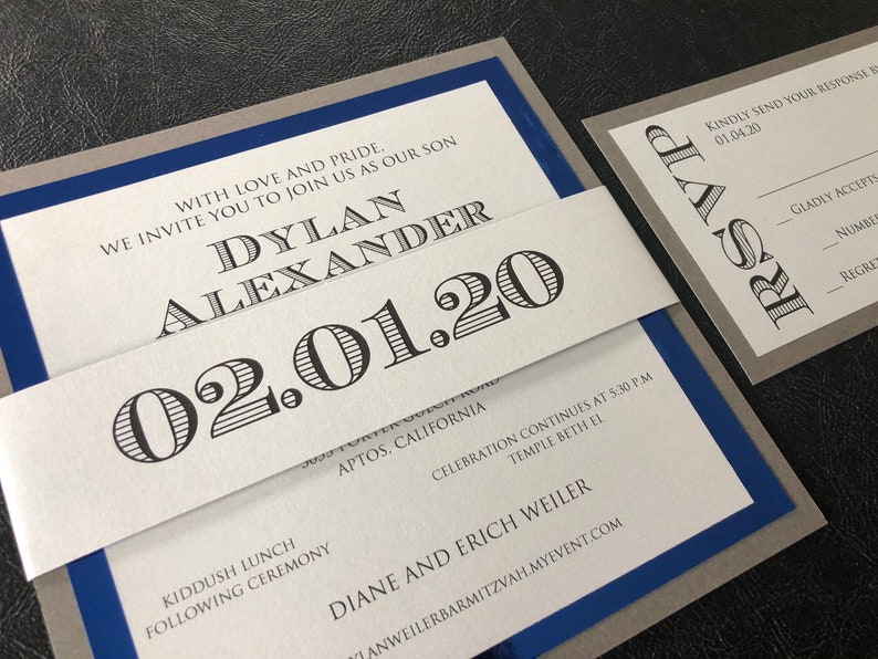 May include: A white and grey invitation with a blue border. The invitation is for a Bar Mitzvah for Dylan Alexander on 1st February 2020. The invitation includes the date, location, and RSVP information.