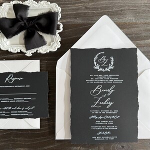 May include: Elegant wedding invitation suite featuring a black invitation card with white calligraphy, a response card, and a white envelope. A black bow sits atop a decorative white tray. The invitation includes the names "Beverly & Zachary".