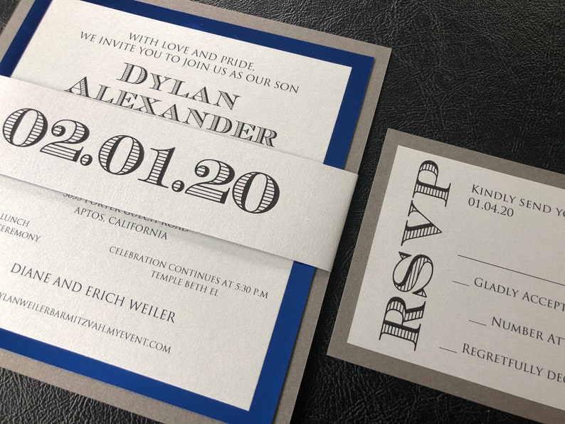 May include: A grey and blue invitation with a white inner layer. The invitation is for a Bar Mitzvah for Dylan Alexander on 1st February 2020. The RSVP card is grey with black text and asks guests to RSVP by 4th January 2020.