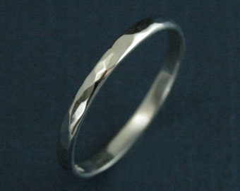 May include: A silver ring with a hammered texture. The ring has a simple, elegant design and a polished finish. The band is approximately 2 mm wide.
