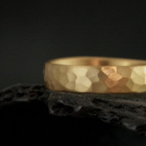 May include: A gold hammered wedding band with a textured surface.