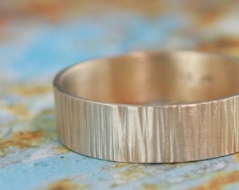 May include: A gold wedding band with a textured, wood-like finish.