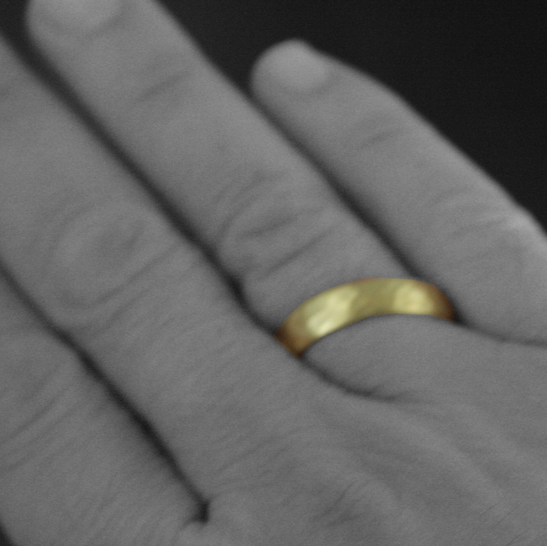 May include: A gold wedding band on a finger.