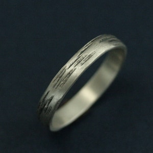 May include: A silver band ring with a textured, brushed finish. The ring has a simple, modern design.