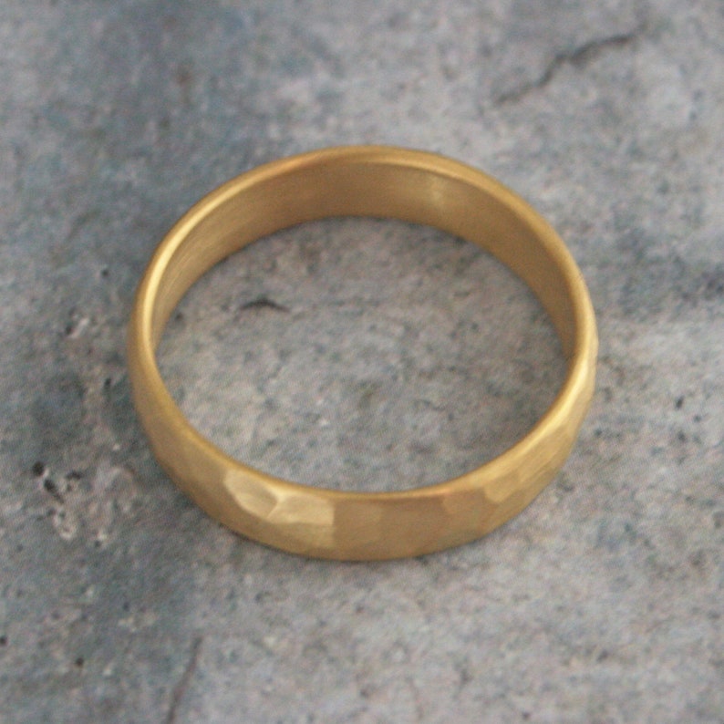 May include: A gold hammered wedding band. The band is smooth and shiny with a hammered texture.