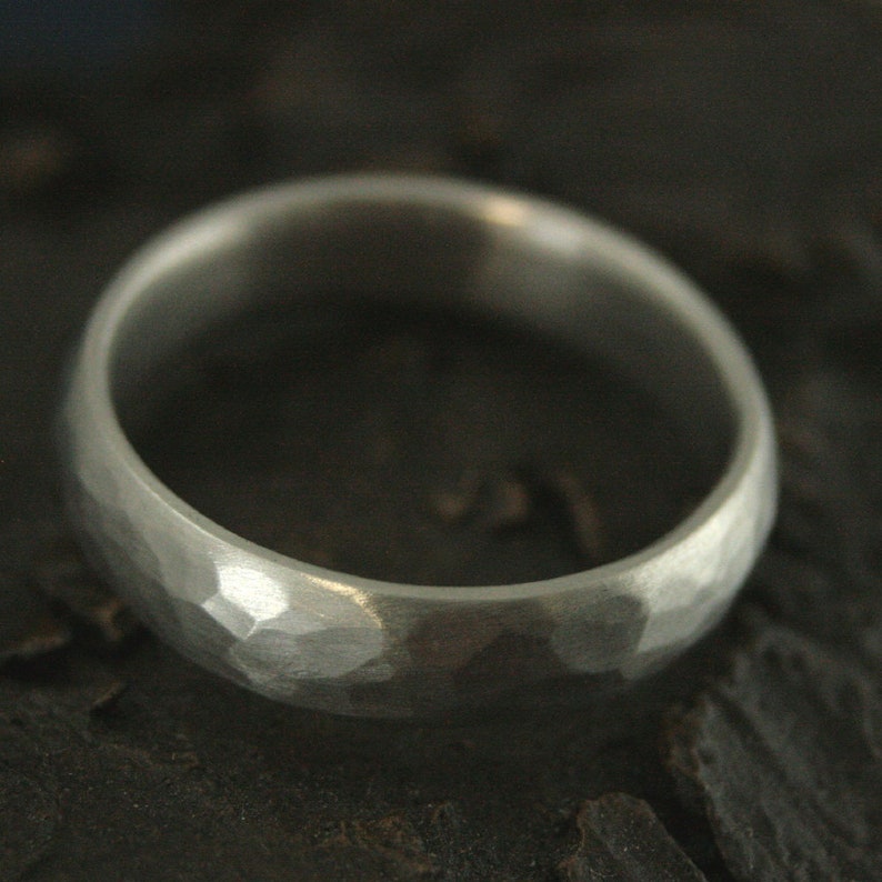 May include: A silver hammered wedding band with a smooth, polished finish.