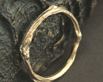 May include: A gold-toned ring made of twisted metal, resembling a branch or twig.