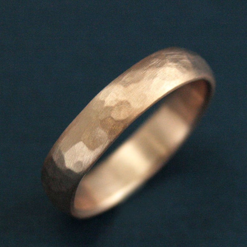 May include: A hammered rose gold wedding band. The band has a matte finish and a slightly rounded profile.