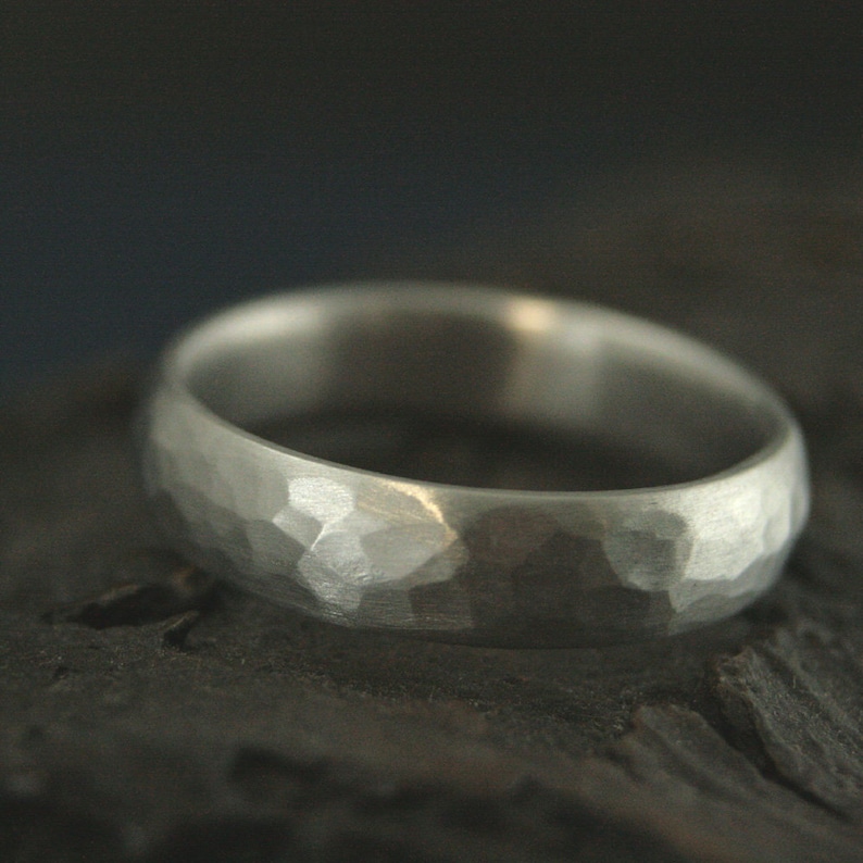 May include: A silver hammered wedding band with a rounded profile.