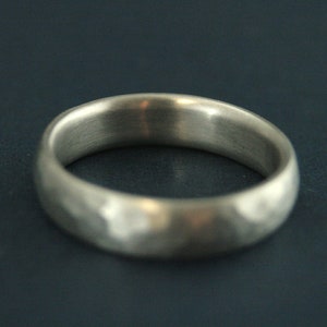 May include: A silver ring with a hammered texture. The ring is smooth and polished on the inside.