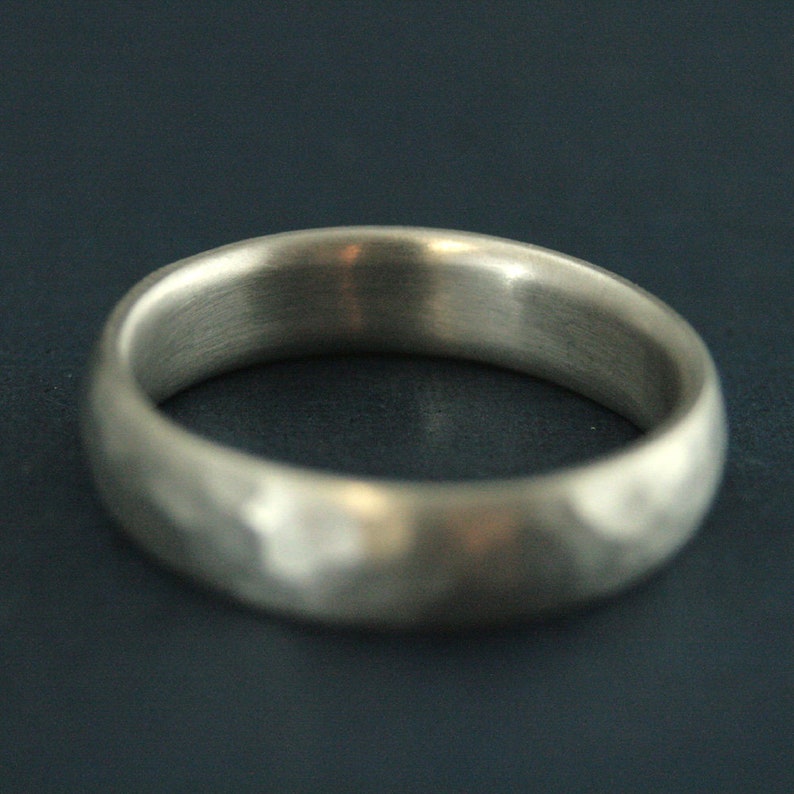 May include: A silver ring with a hammered texture. The ring is smooth and polished on the inside.