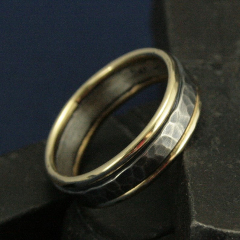 May include: A hammered silver band with a double band of gold around the edge.