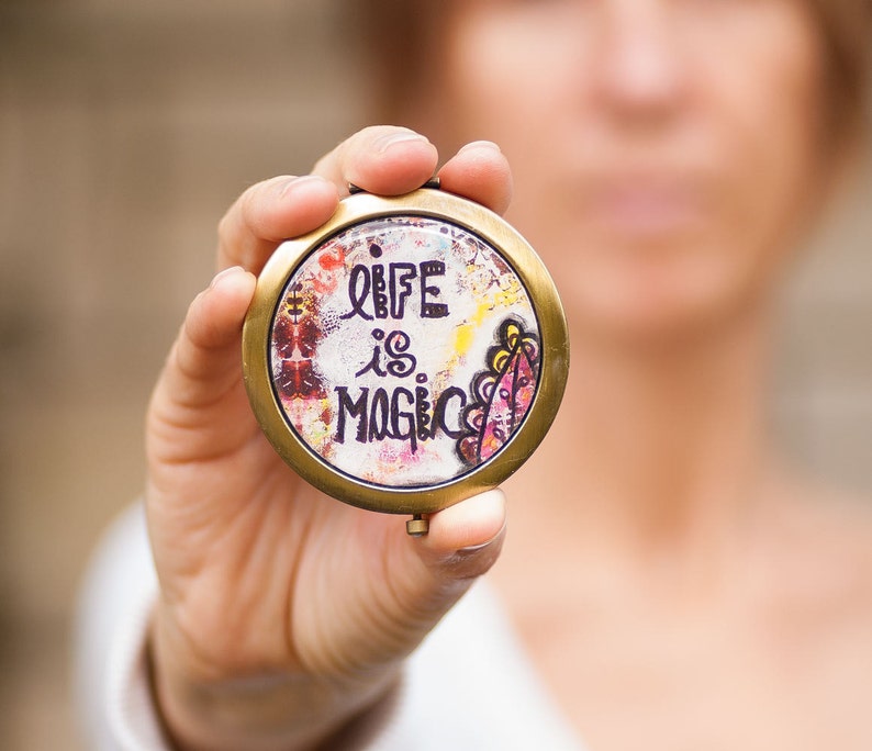 May include: A gold-colored compact mirror with a colorful design and the text "Life is Magic".