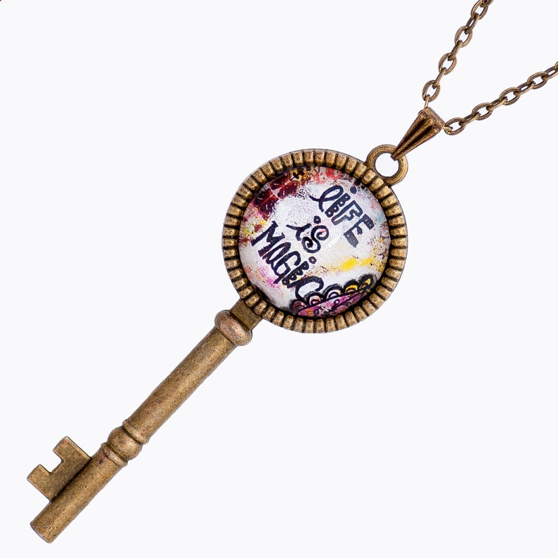 May include: A gold key necklace with a round pendant featuring a colorful design and the text "Life is Magic".