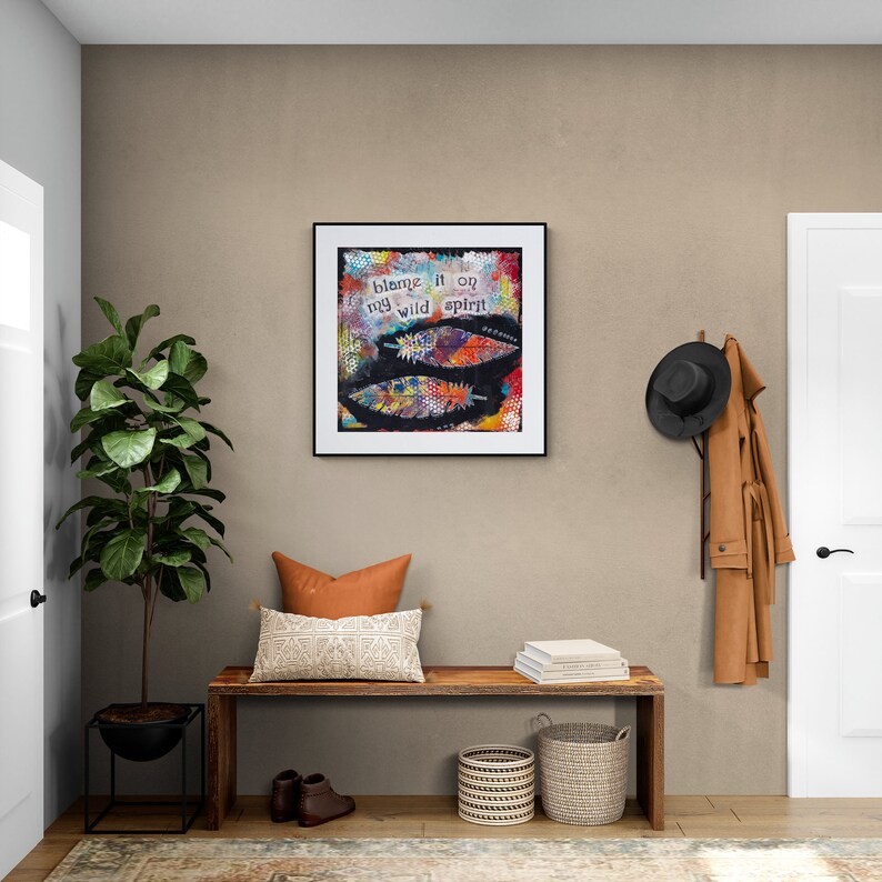 Puede incluir: Un banco de madera con un coj&iacute;n marr&oacute;n, un soporte de planta negro con una planta verde, dos cestas tejidas y una impresi&oacute;n enmarcada con el texto "blame it on my wild spirit".