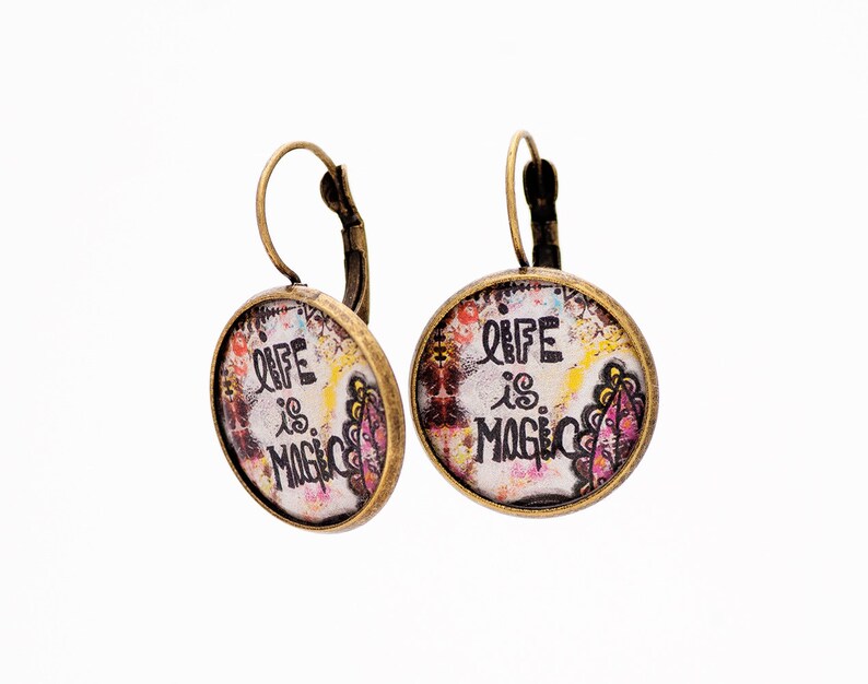 May include: A pair of bronze earrings with a round, colorful, glass charm that says "Life is Magic".