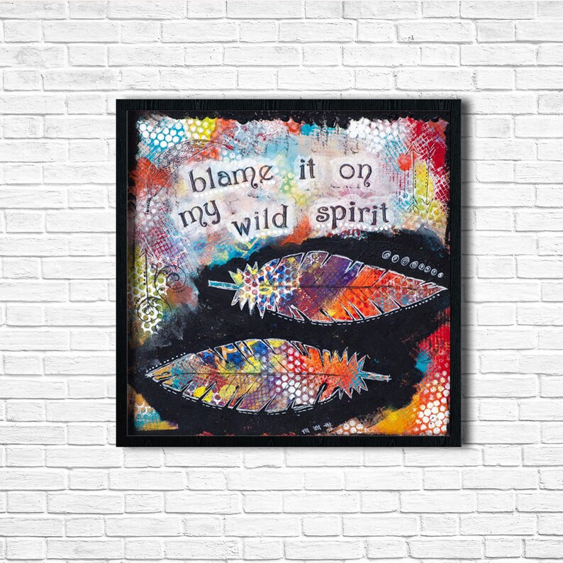 Puede incluir: Una impresi&oacute;n de arte enmarcada en negro con un fondo abstracto colorido y dos plumas estilizadas. El texto "blame it on my wild spirit" est&aacute; escrito en blanco sobre el fondo.