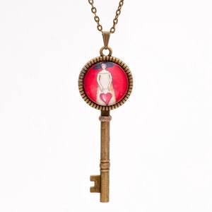 May include: A gold key necklace with a round pendant featuring a woman holding a red heart on a red background.