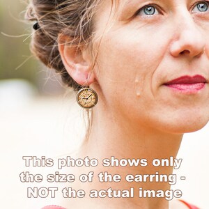 May include: A pair of gold-toned earrings with a round, clock-face design. The earrings are small and delicate.