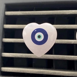 May include: A pink heart-shaped charm with a blue evil eye design. The charm is made of rose quartz and is a popular symbol of protection and good luck.