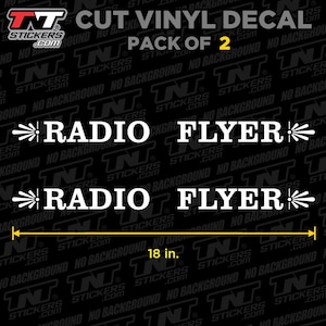 May include: Cut vinyl decal, pack of 2, featuring the text "RADIO FLYER" in white, with decorative elements on each side. The decal measures 18 inches in length. The background is black.