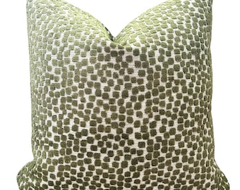 May include: A square decorative pillow with a textured pattern of olive green squares on a white background. The pillow has a soft, plush appearance, perfect for adding a touch of comfort and style to any living space.