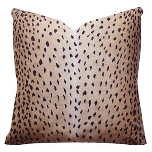 May include: A beige throw pillow with a black and white spotted pattern. The spots are small and scattered across the pillow.