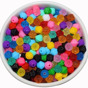 May include: A bowl filled with colorful, textured, round plastic beads. The beads are in various shades of red, orange, yellow, green, blue, purple, pink, and black.