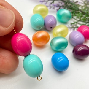 May include: Assortment of oval-shaped beads in various colours, including pink, blue, green, purple, yellow, and orange. The beads are strung on a gold wire.