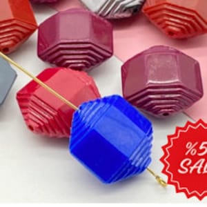 May include: Assortment of colorful faceted glass beads with a geometric design. The beads are strung on a gold wire. The beads are available in red, blue, purple, and gray.
