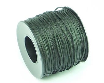 Puede incluir: Una bobina de cordón encerado verde oscuro, enrollada apretadamente en una bobina de metal.