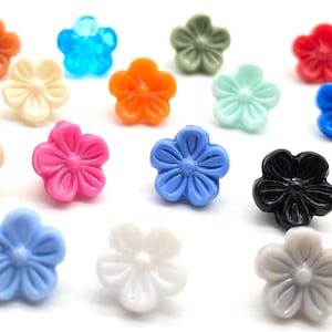 Könnte beinhalten: Sortiment von 15 bunten, plastikblumenförmigen Knöpfen. Die Knöpfe sind in verschiedenen Farben, darunter Blau, Grün, Pink, Orange, Weiß und Schwarz.