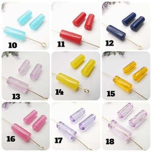 May include: Assortment of 10 different colors of glass beads, each color is shown in a row of 3 beads. The beads are all the same size and shape, and they are all translucent. The colors are: light blue, red, dark blue, light purple, yellow, orange, pink, light purple, lavender, and light pink.