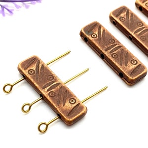 May include: Three antique gold-toned metal connector pieces with a decorative etched pattern. Each piece has three holes and is attached to a gold-toned metal loop.