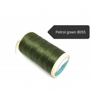 May include: A spool of petrol green thread, color code 8055, against a white background. The thread is tightly wound on a cardboard spool with a white and blue label. The thread has a slight sheen.