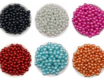 May include: Six bowls filled with colorful beads. The beads are in various colors: black, white, hot pink, red, light blue, and orange. The beads are round and appear to be made of plastic or glass.