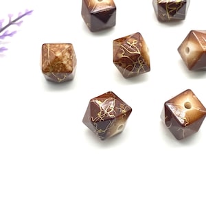 Könnte beinhalten: Sechs braune und weiße facettierte Perlen mit goldenen Akzenten. Die Perlen haben ein Loch in der Mitte zum Auf fädeln.