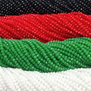 May include: Close-up of strands of faceted beads in black, red, green, and white. The beads are small and evenly sized, creating a textured surface. The beads are likely for jewelry making or crafting.