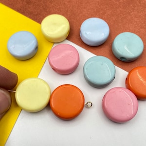Könnte beinhalten: Sortiment an bunten runden Perlen mit Löchern zum Auf fädeln. Die Perlen sind in den Farben Gelb, Rosa, Blau und Orange.
