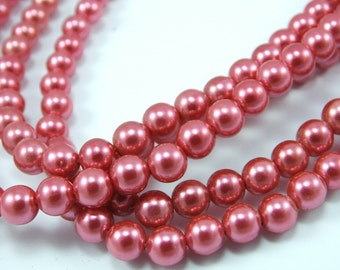 May include: A strand of pink pearl beads. The beads are round and have a smooth, glossy finish.