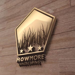 A gold pentagonal logo with grass and three stars, and the text "MOWMORE LANDSCAPING" in raised letters, mounted on a textured brown wall.