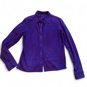May include: A long-sleeved button-down shirt in a vibrant purple suede material. The shirt features a classic collar, a front button placket with matching purple buttons, and buttoned cuffs. The label inside the collar reads Ralph Lauren Sport.